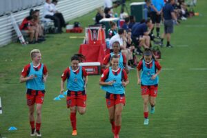 Five female soccer players doing warm ups exercise wearing blue training bibs: Warm-up Exercises and Cool-down Routines