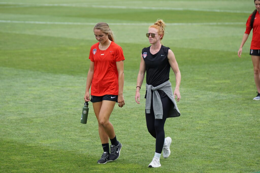 A female footballer walking beside her soccer coach during a football training session: best female soccer coaches