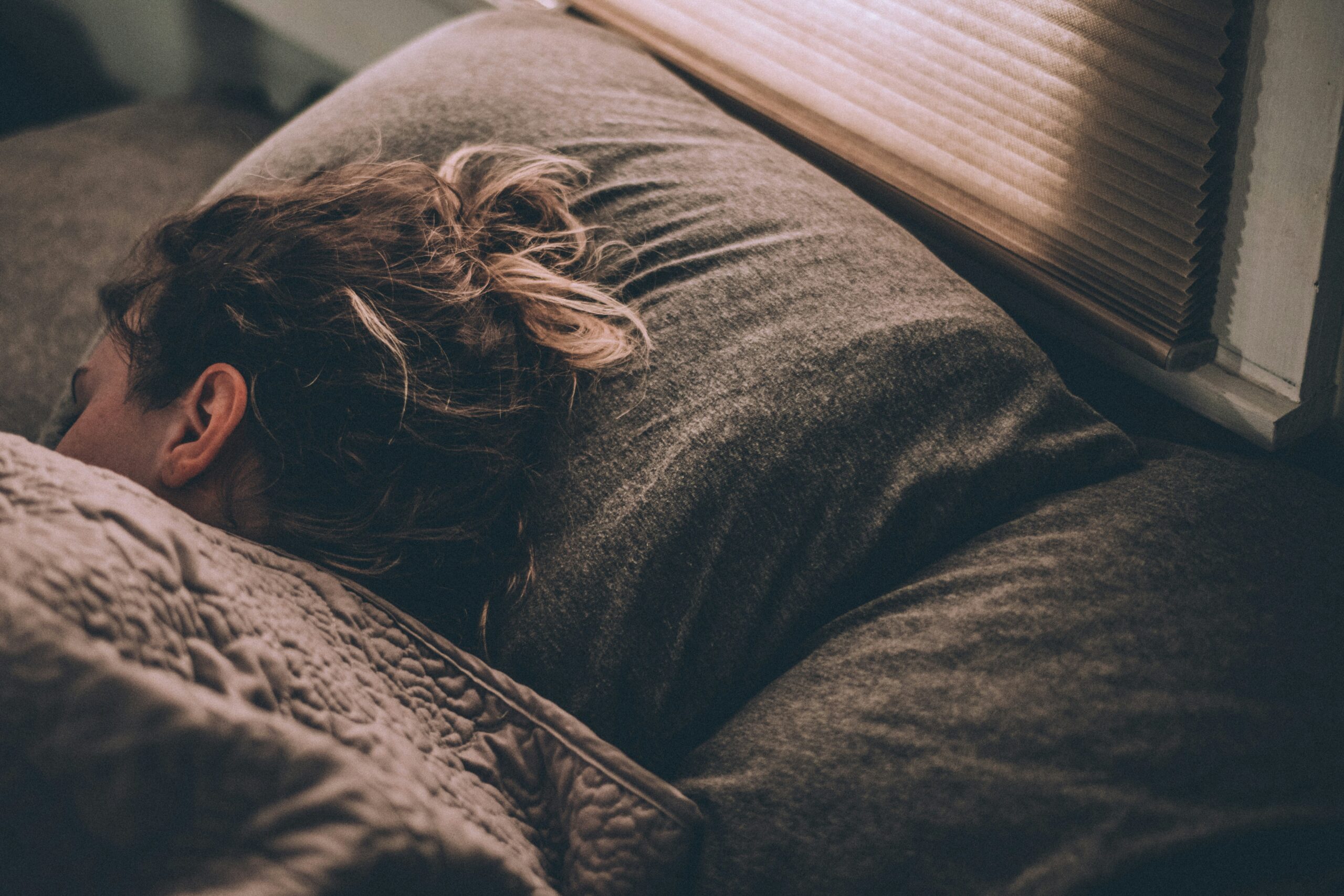 A women sleeping on bed under blankets: Poweful sleeping habits to boost perfomance