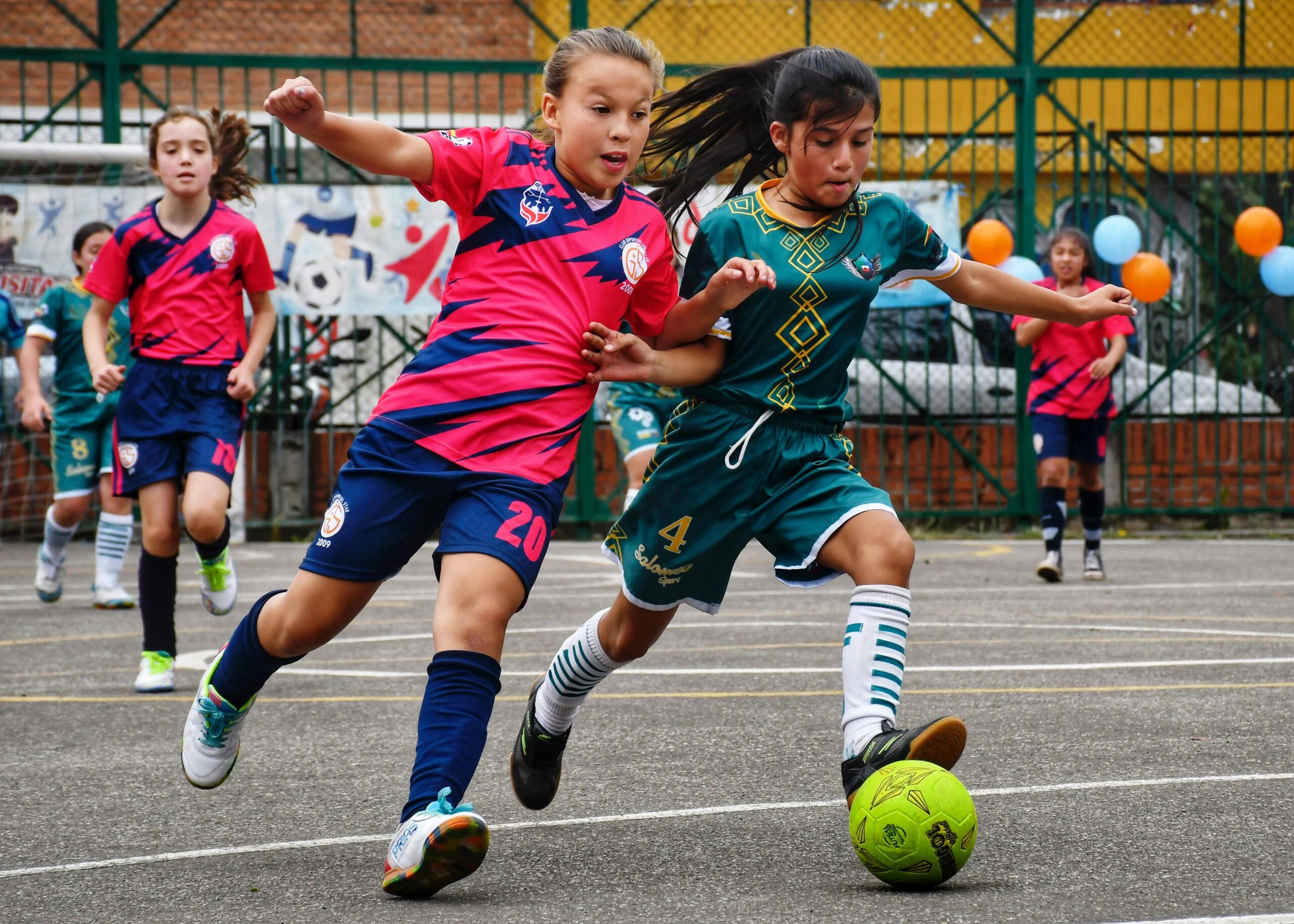 Two soccer girls competing over a soccer ball on a green soccer field: Best Agility and Footwork Drills