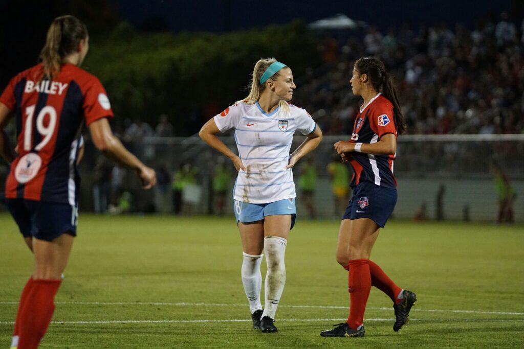 A women soccer player disappointed walking on the pitch sorrounded by opponents: setbacks in soccer