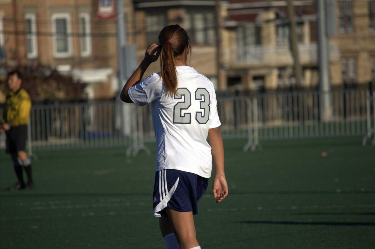 A female soccer babe with a navy blue short and white jersey on a soccer pitch: Ups and Downs of Learning Soccer