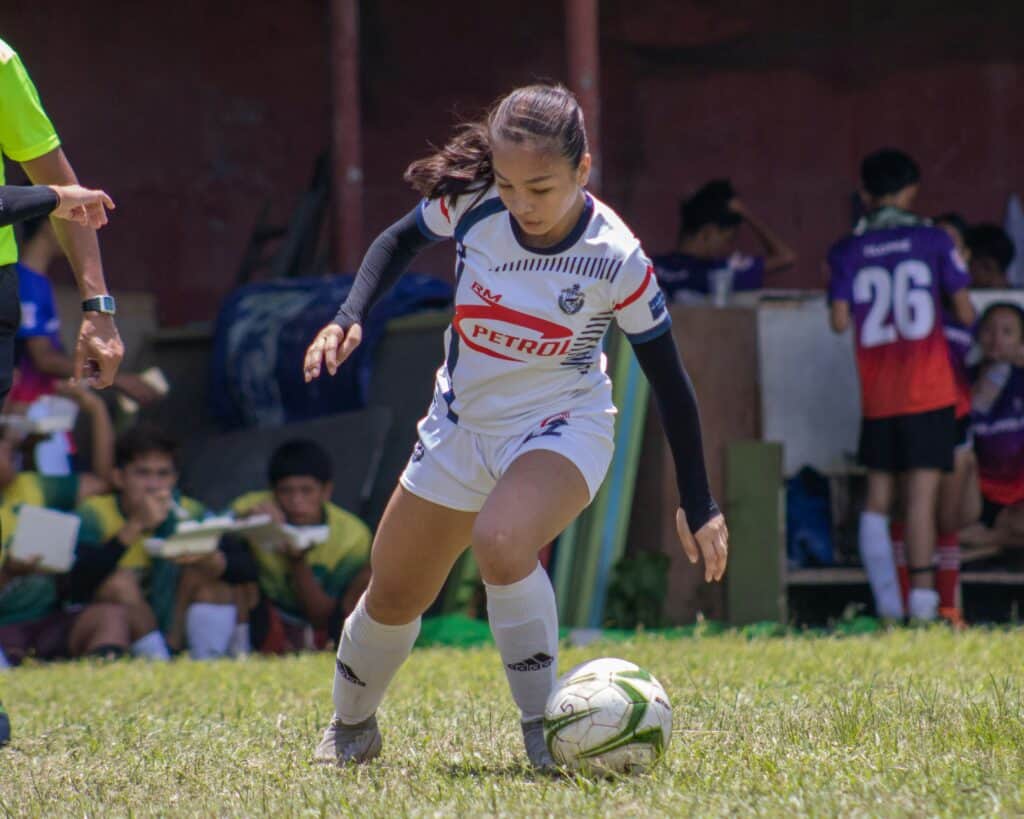 A young soccer girl playing a soccer ball on a soccer field: Rewarding Parts of Learning Soccer 