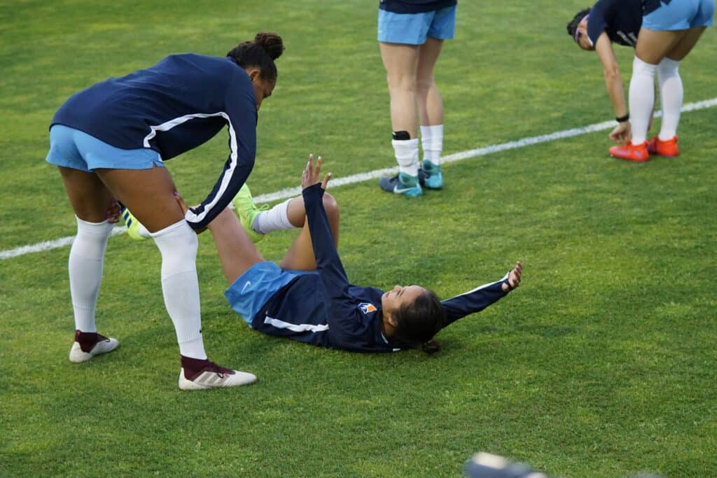 Two female soccer player with onne lying on the grass beside her teammate: Ups and Downs of Learning Soccer