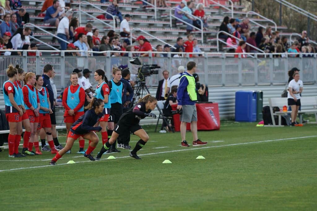 Two women soccer players doing soccer drills using cones on a green pitch: Rewarding Parts of Learning Soccer