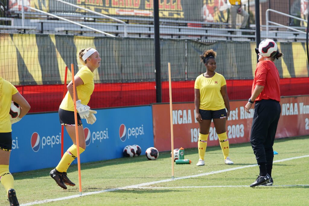 A female soccer coach alongside female soccer players on training during daytime: Women's Football Career Guide