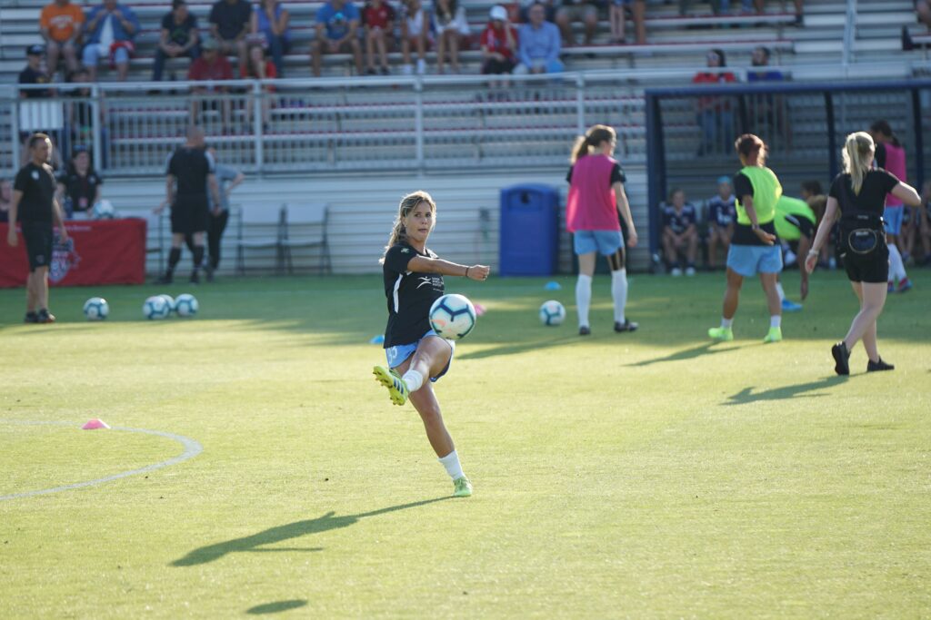 A female soccer player doing soccer drils on a green pitch: soccer corner kick