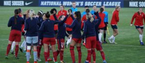A group of women soccer players standing on a green pitch alongside soccer referees on a women's football matchday: soccer career opportunities for women