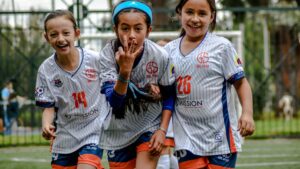 Young soccer girls celebrating with a three finger signs during a women soccer day match: How to Balance Soccer with School