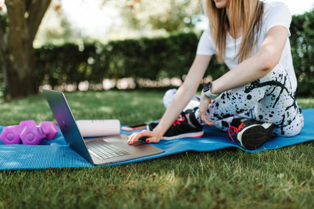 shallow focus photo of a woman in activewear using a laptop while sitting on a yoga mat outside during daytime: How to Balance Soccer with School