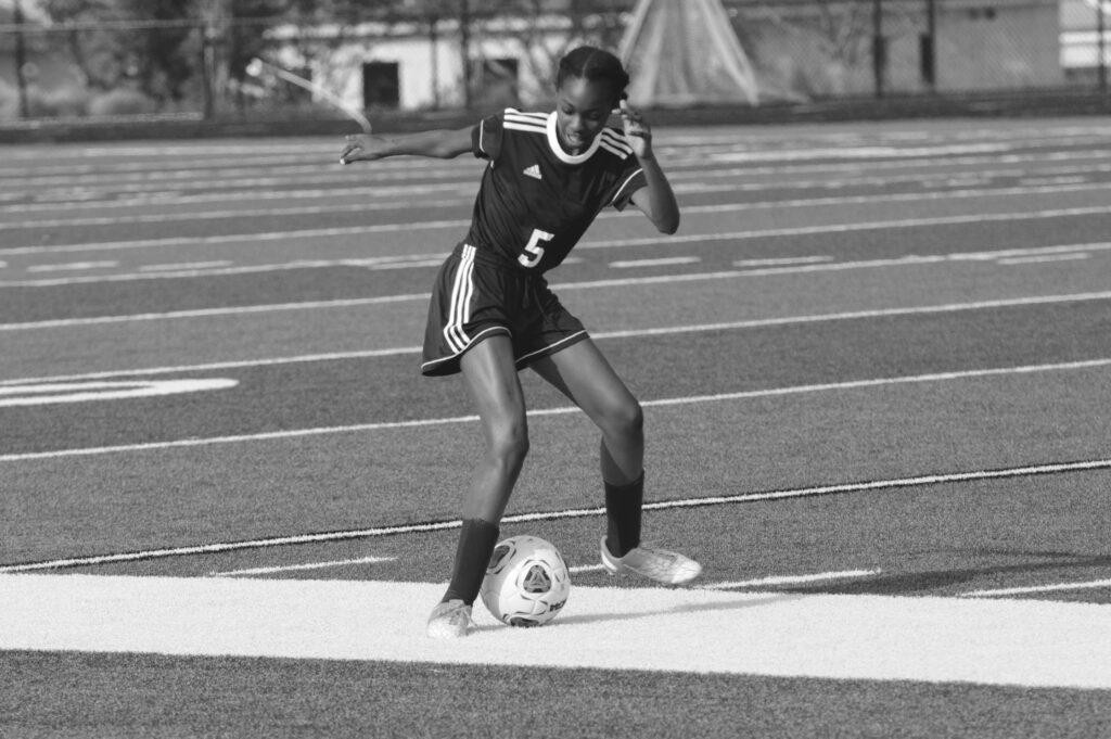 A grayscale photography of woman playing soccer: African girls quit football