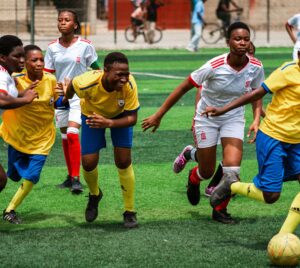 Two team of african soccer girls playing football during daytime