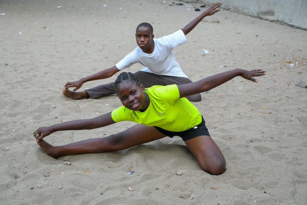 a black boy and girl doing streches on the sand
