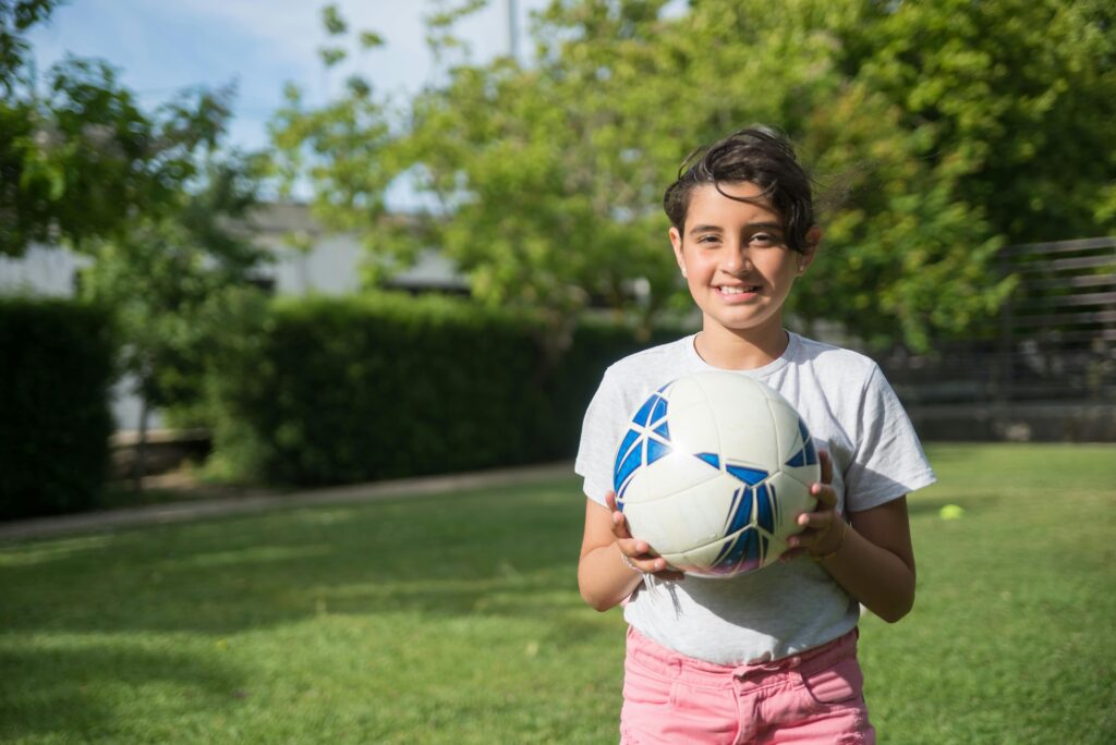 Smiling soccer girl holding a soccer ball